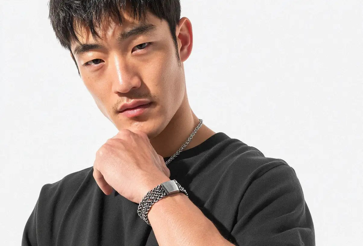 A close-up of a man modeling a stylish Stainless Steel Bracelet, paired with a matching necklace.