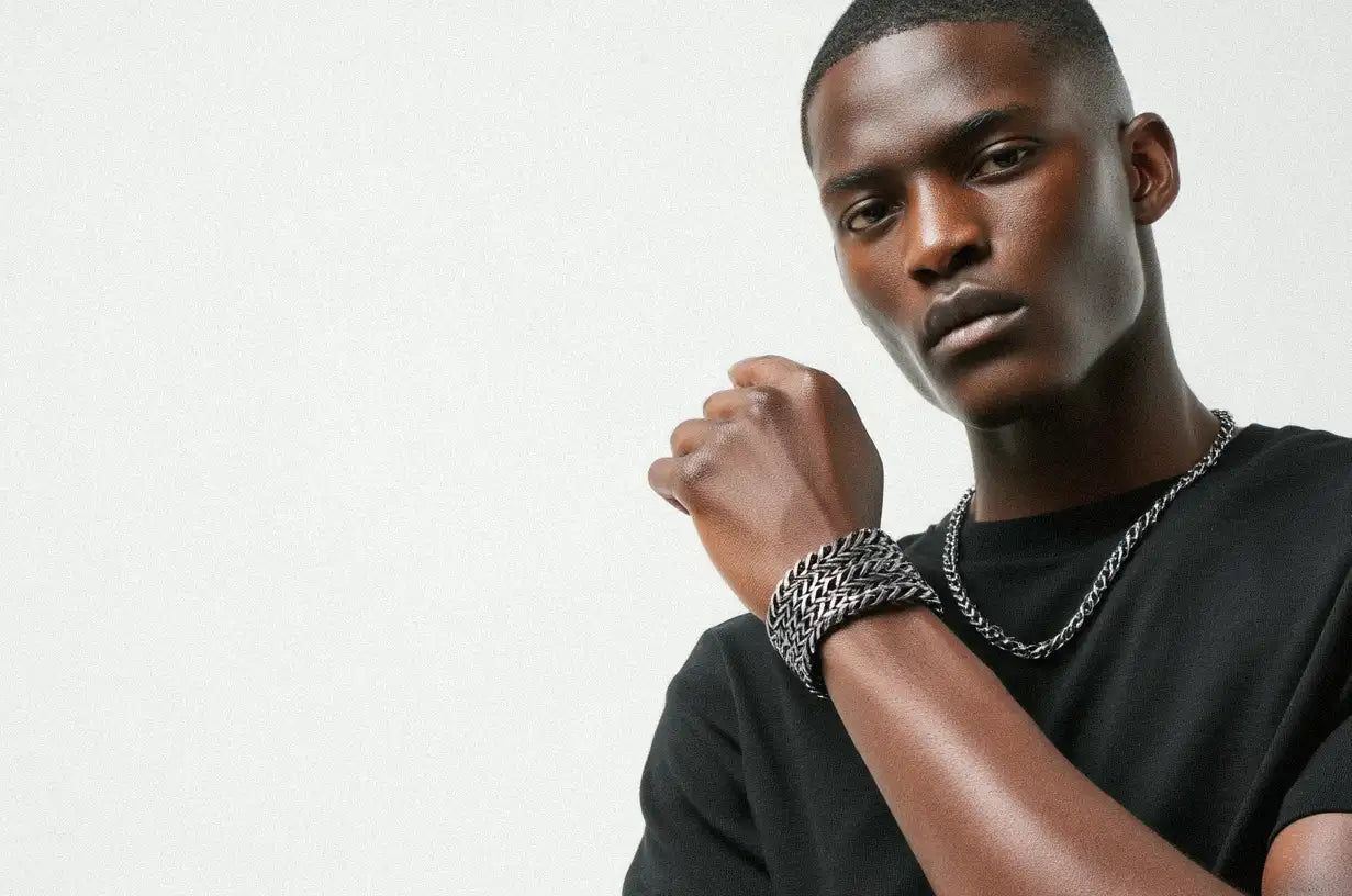 A striking portrait of a man showcasing a stacked, multi-layer Stainless Steel Bracelet alongside a chain necklace.