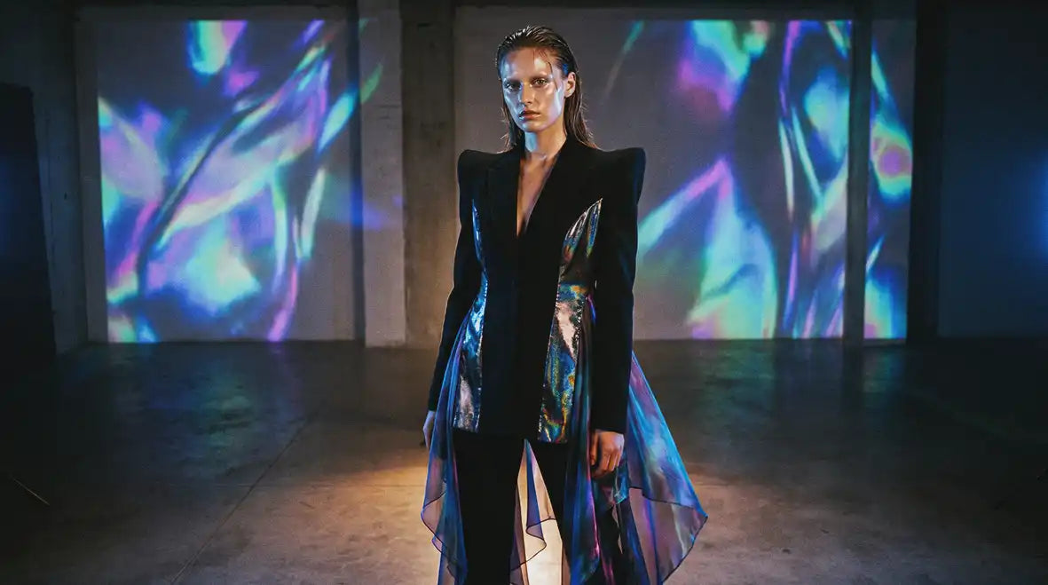Contemporary avant-garde fashion 2026 with sculptural black tailoring and iridescent oil-slick panels against holographic projections, new wave designer style