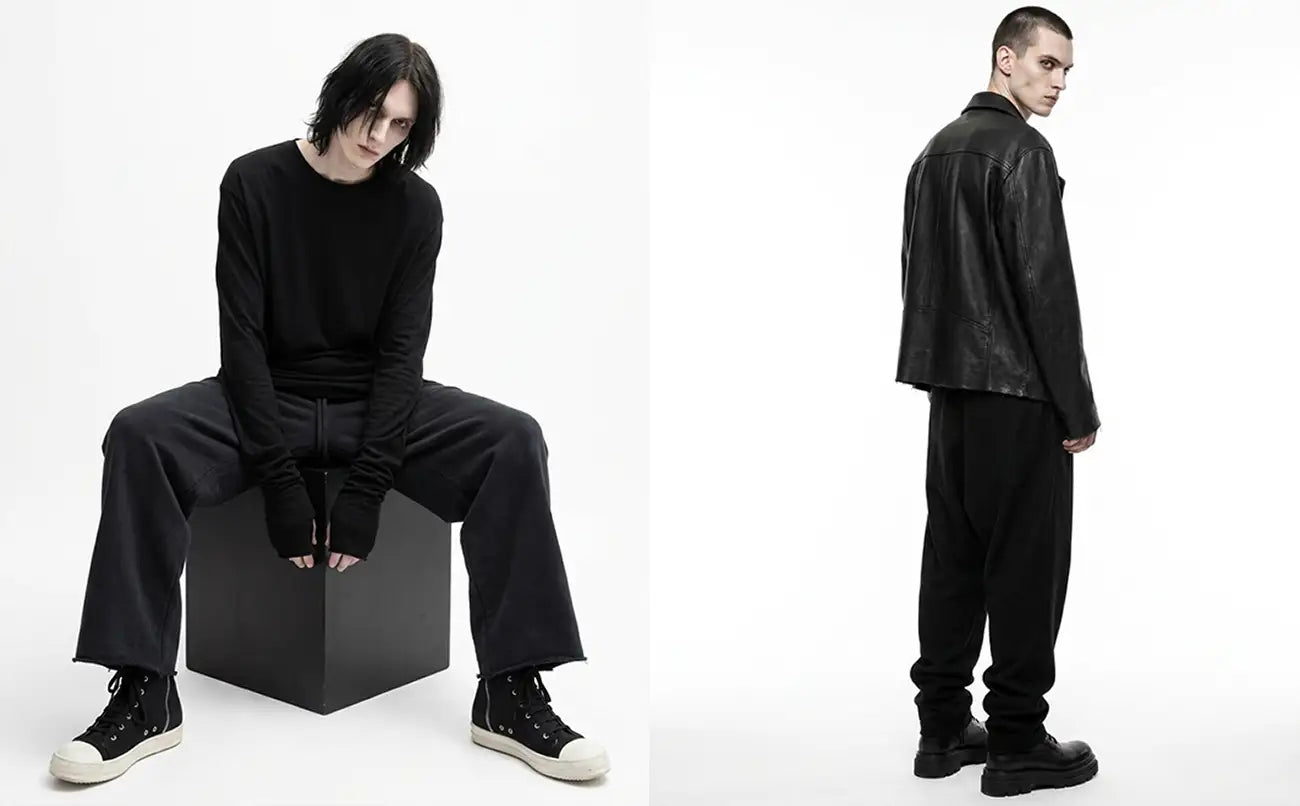 Dark avant-garde streetwear lookbook with male model in oversized black jersey and dropped-crotch sweatpants seated on cube and leather jacket with platform boots, Rick Owens DRKSHDW style