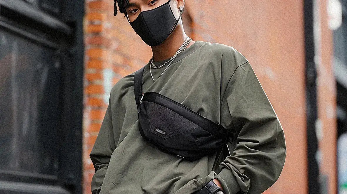 an asian man wearing a techwear fanny pack in front of a wall