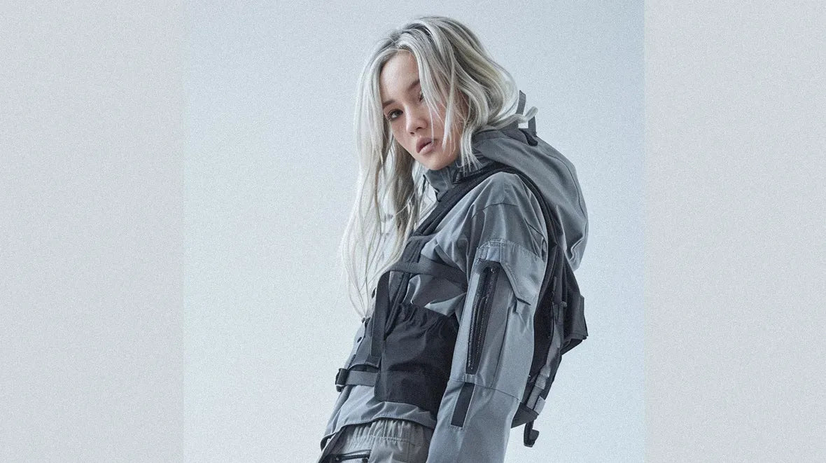 a blonde woman in grey techwear outfit