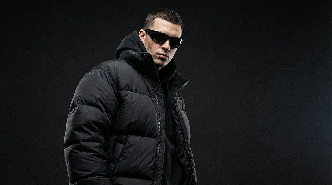 Man in black puffer jacket wearing narrow futuristic techwear sunglasses with sleek cyberpunk aesthetic
