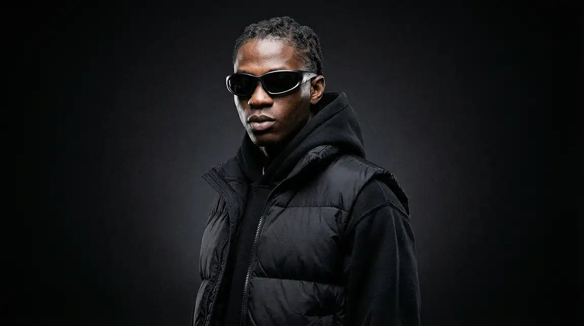 Man in black puffer vest wearing wrap-around techwear sunglasses with white frame and dark tinted lenses