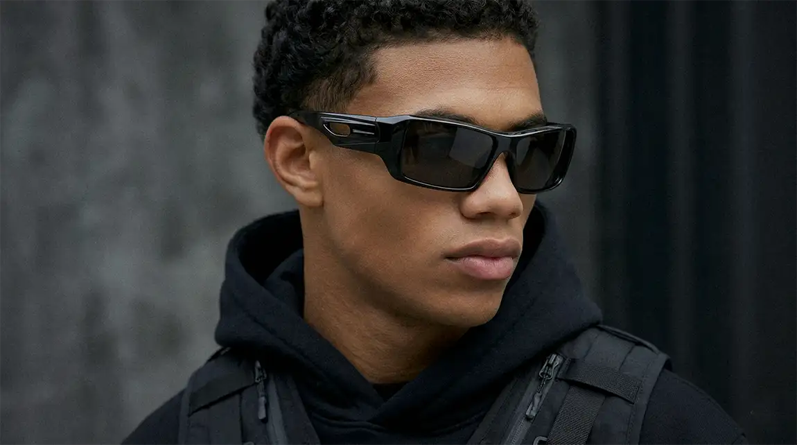 Young man wearing angular black techwear sunglasses with bold rectangular cyberpunk frame